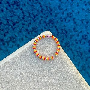 A clay bead bracelet that is homemade and is red, yellow, and orange!